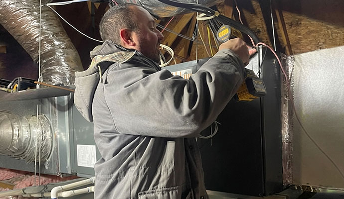 Expert repairing an indoor air handler system in an attic