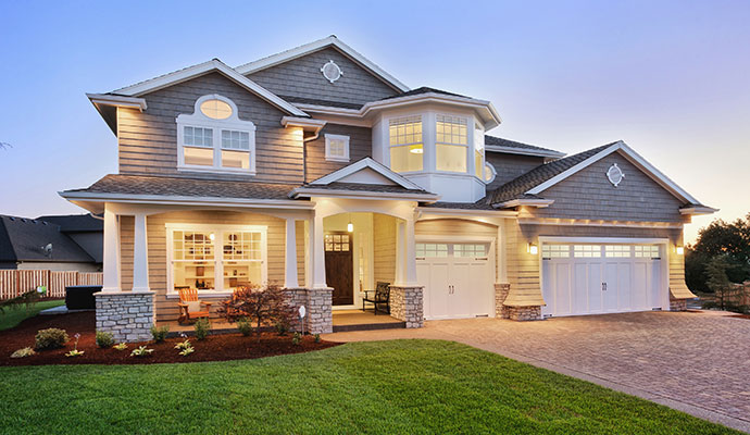 Modern home with windows and a paved driveway at dusk
