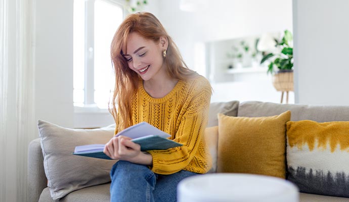 woman reading book on sofa