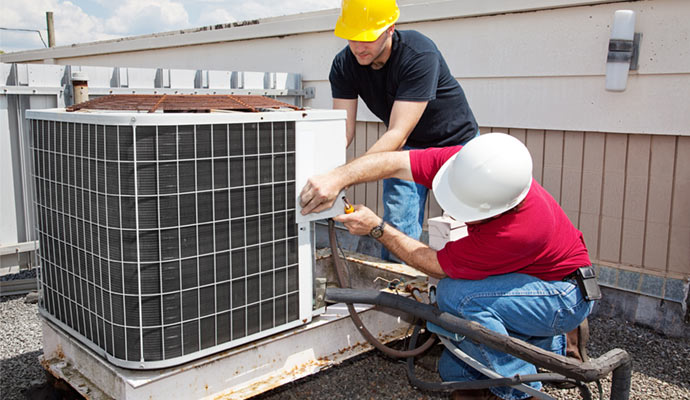 Professionals installing central air conditioning system on a rooftop.